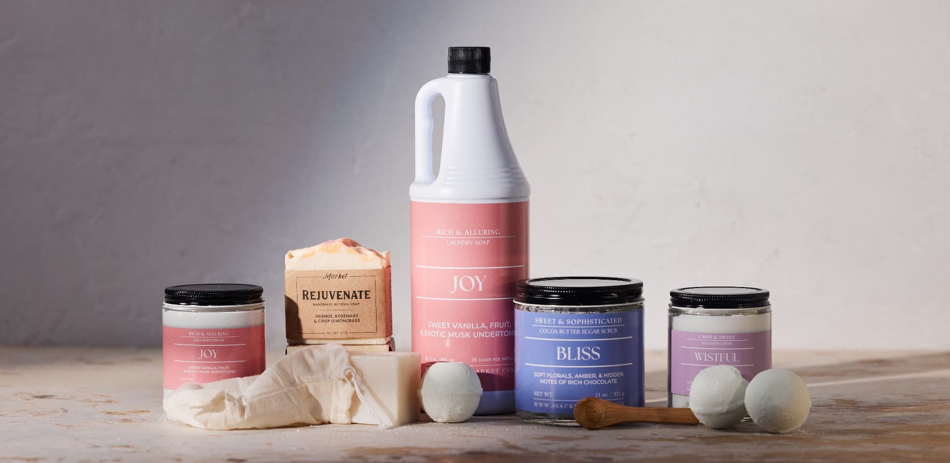 Row of pink and lavender bath products, soap bars, and bath bombs on a stone surface