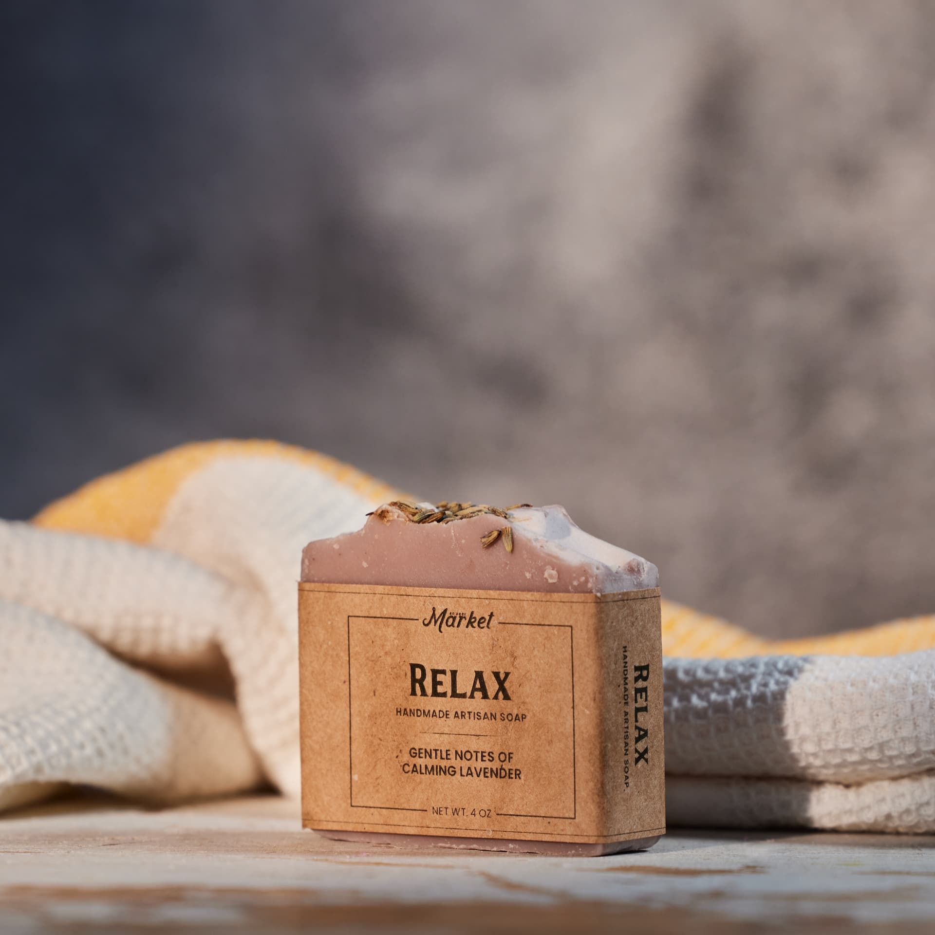 Kraft-wrapped lavender artisan soap bar beside folded waffle towels