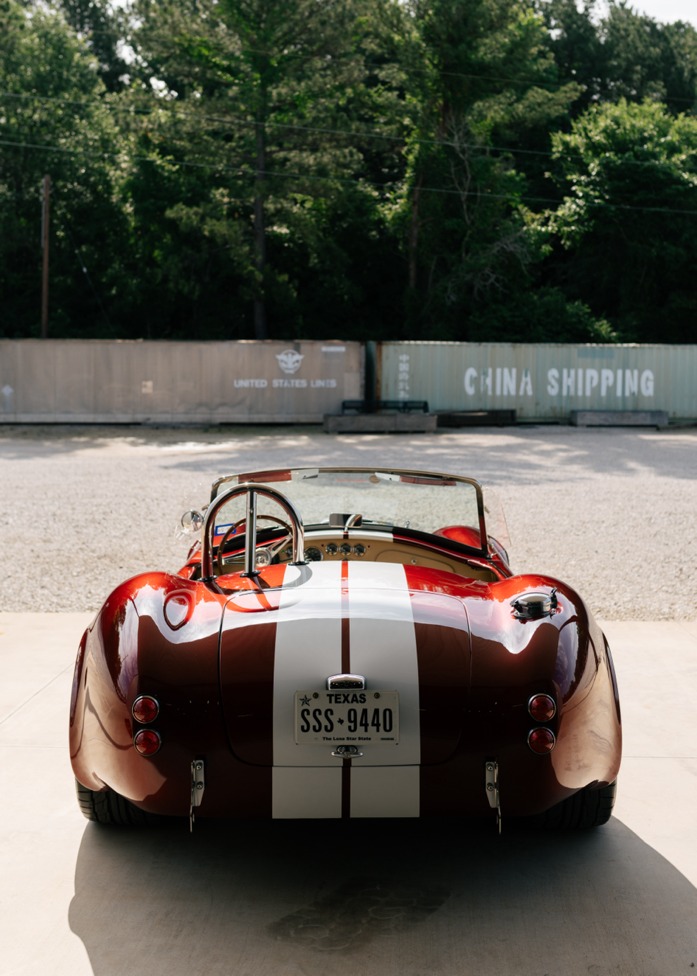 Rear view of a red and white striped Cobra roadster with Texas plate